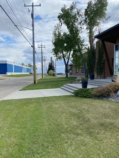 Lawn, planters and ornamental grasses kept neat at a building entrance.