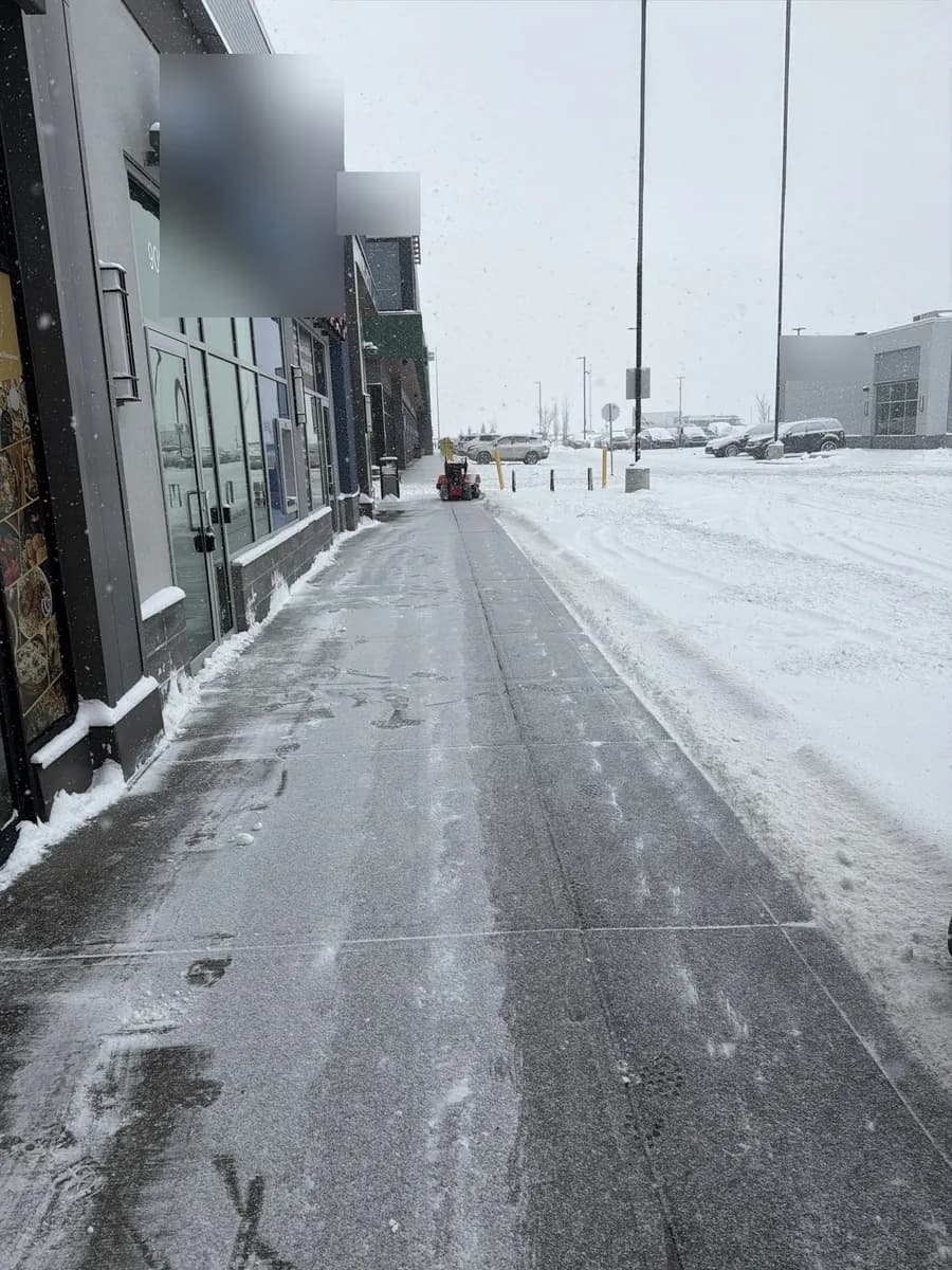 Retail sidewalk, cleared mid-storm — Beast Landscaping, Calgary